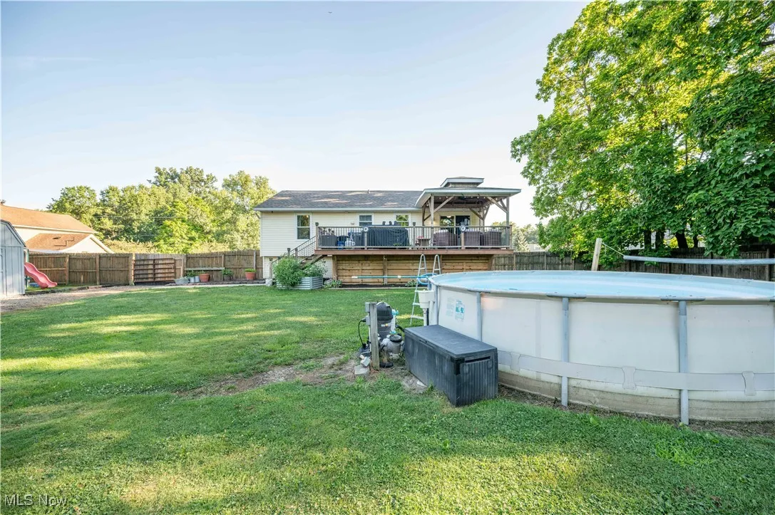 Rear view of property with a wooden deck, a fenced backyard, and stairs