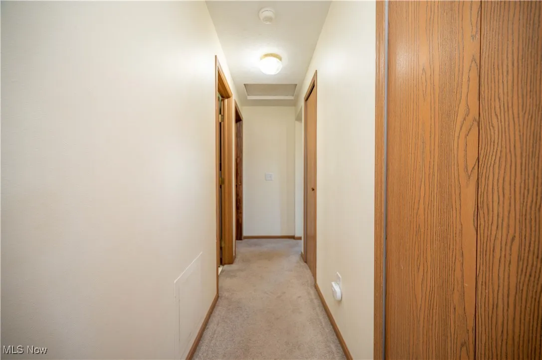 Hall featuring light colored carpet and baseboards