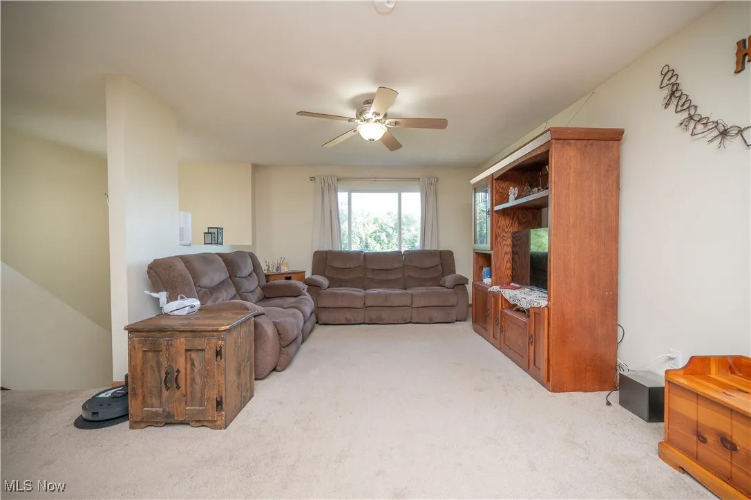 Living room featuring a ceiling fan and light carpet