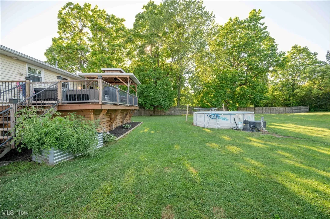 Fenced yard featuring a deck, stairway, and view of scattered trees