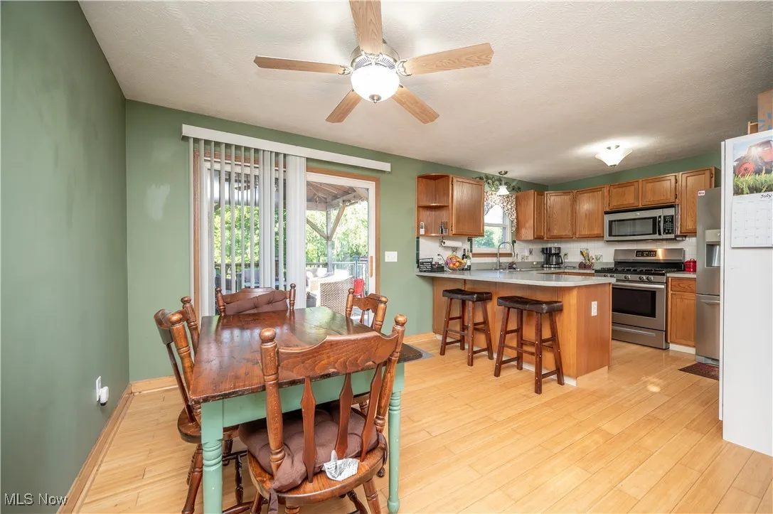 Dining room with light wood-style flooring, ceiling fan, and a textured ceiling