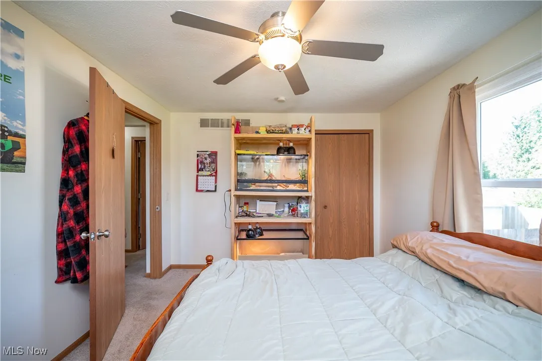 Carpeted bedroom with a ceiling fan and a textured ceiling