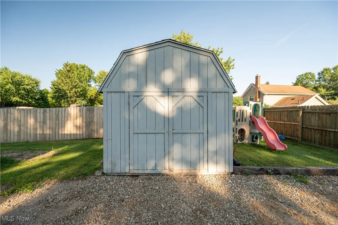 View of shed with a fenced backyard and a playground