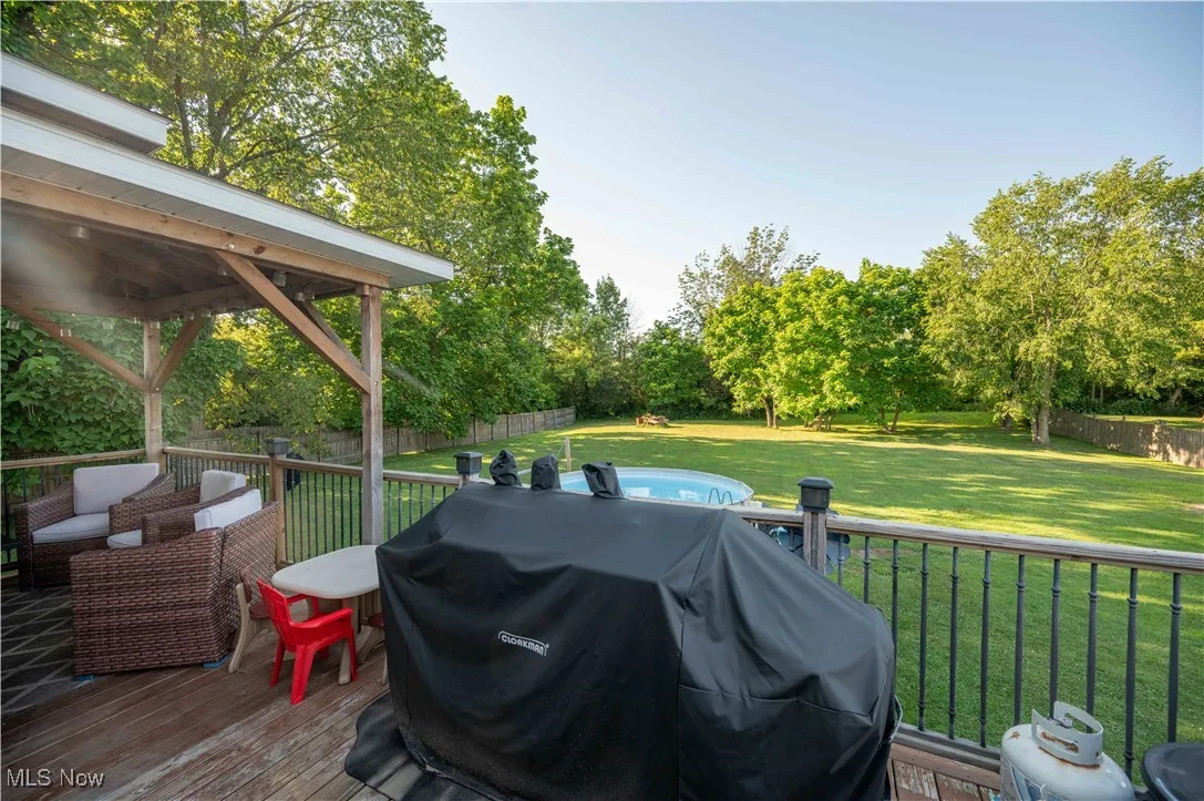 Wooden terrace featuring a grill, a fenced backyard, and view of scattered trees