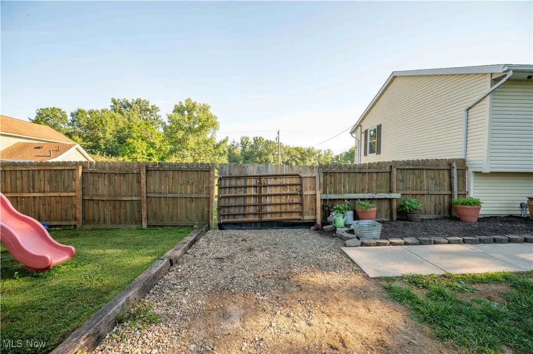 Fenced backyard featuring a playground