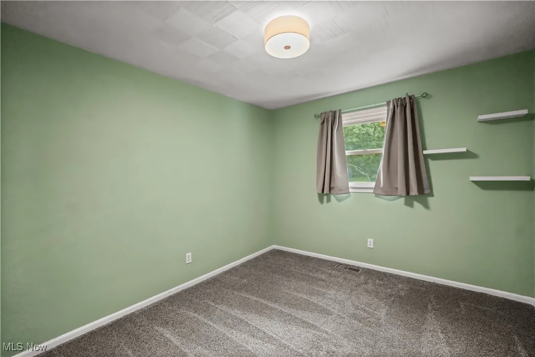 Carpeted spare room featuring baseboards