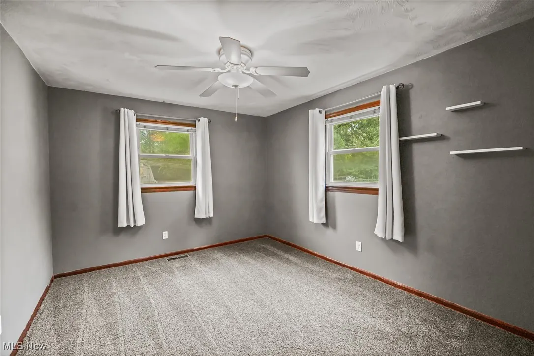 Empty room with carpet flooring, plenty of natural light, and a ceiling fan