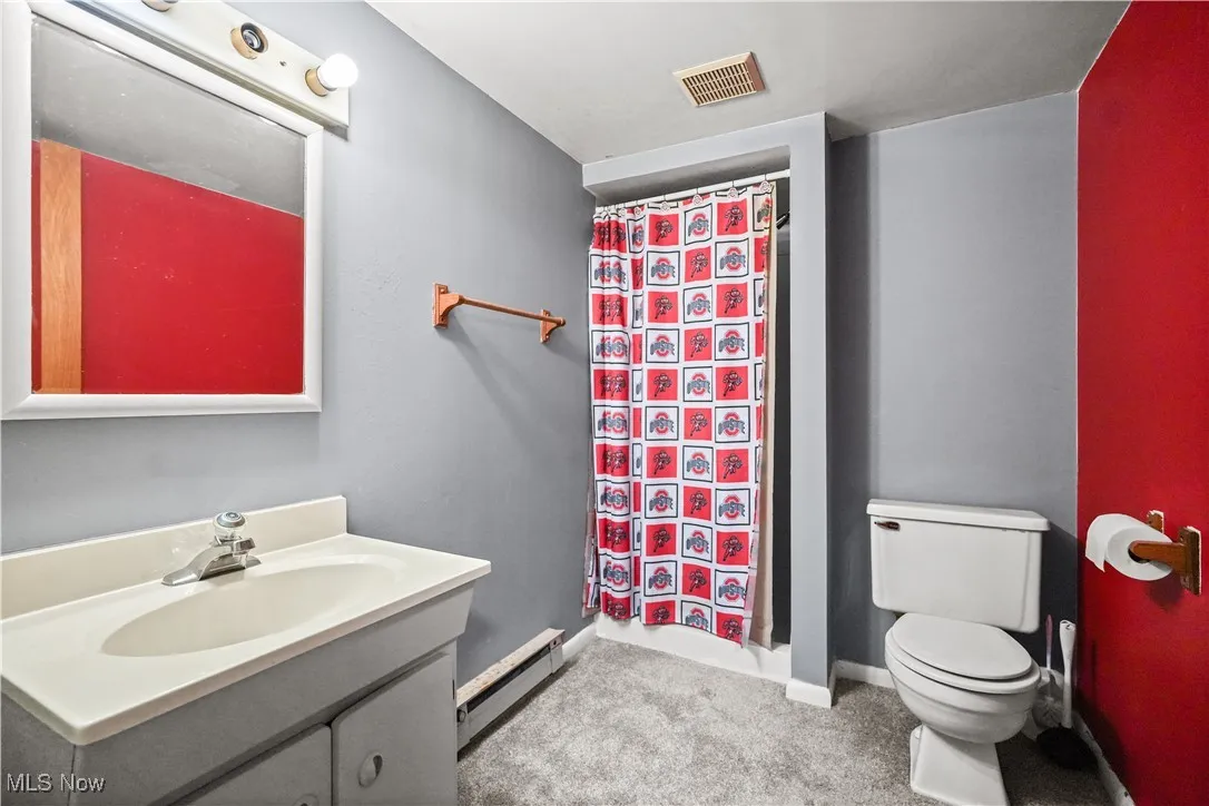 Full bath with a baseboard radiator, vanity, and a shower with shower curtain