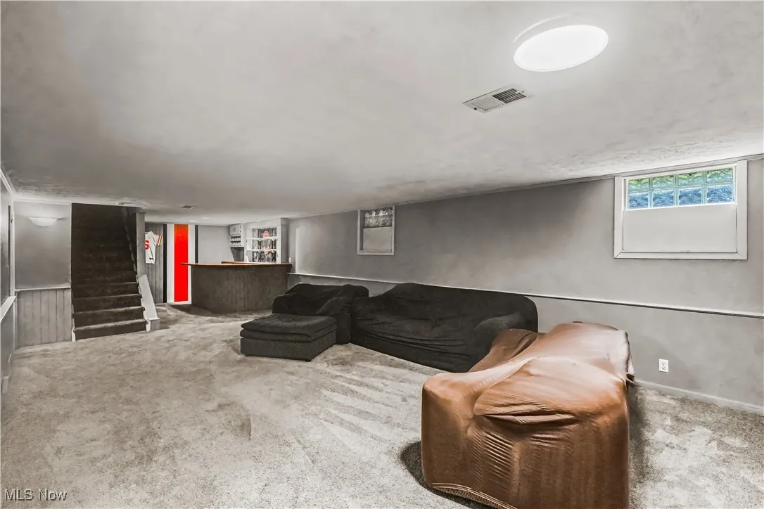 Living room with carpet floors, bar area, and stairs