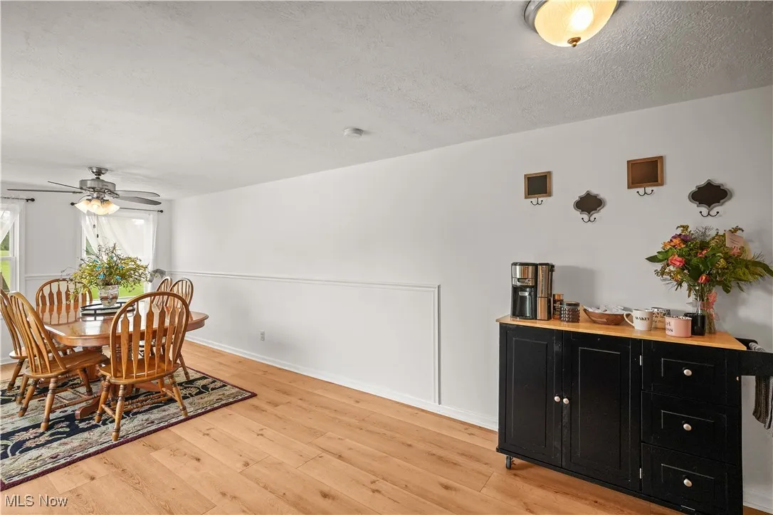 Dining area with light wood-style flooring, a textured ceiling, and a ceiling fan