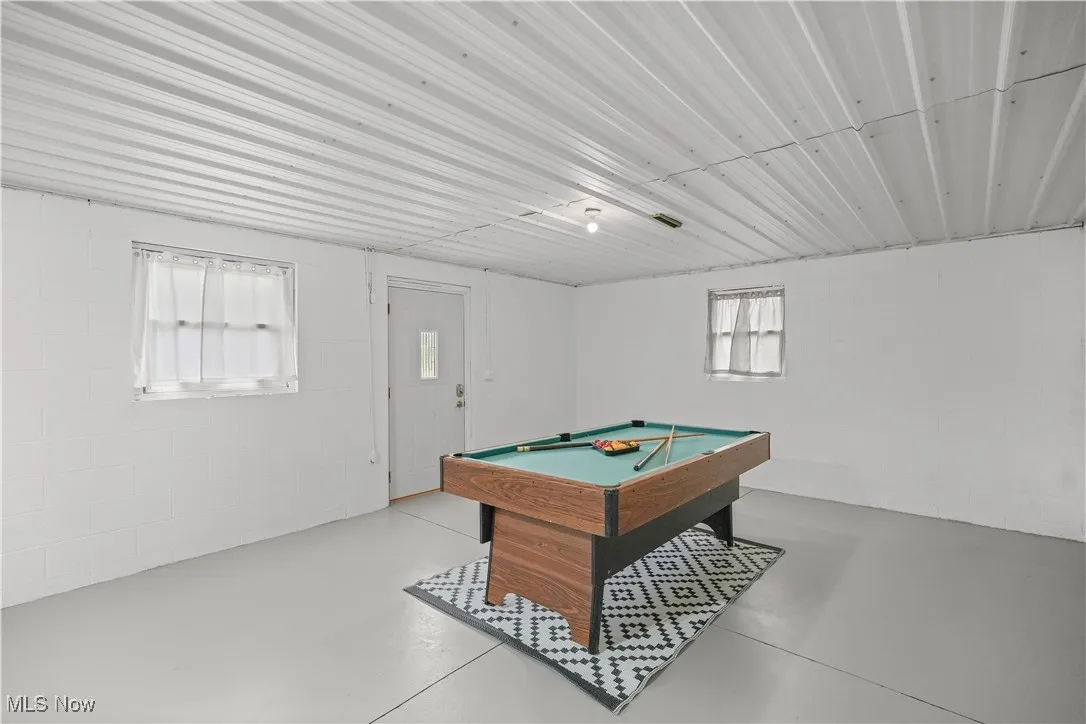 Playroom featuring finished concrete floors, concrete block wall, and billiards table