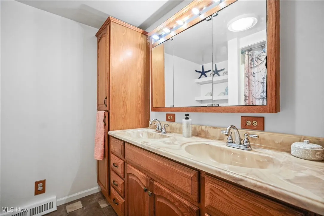 Full bath featuring double vanity and baseboards