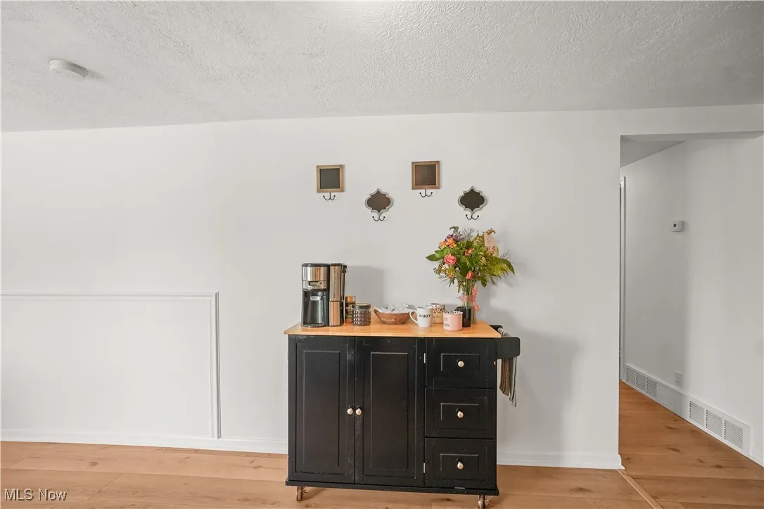 Detailed view of a textured ceiling, wood finished floors, and a smoke detector