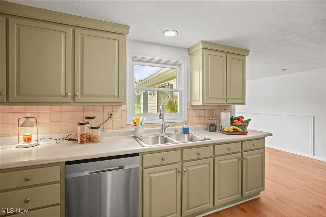 Kitchen with backsplash, dishwasher, light wood-style flooring, and light countertops