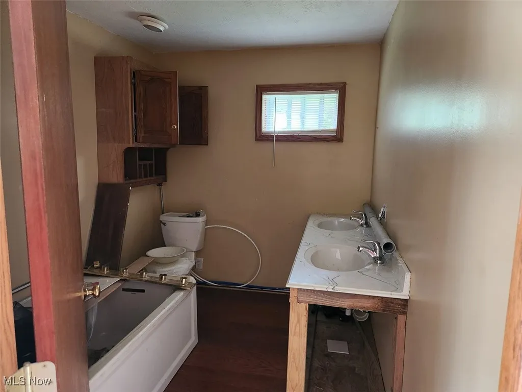 Bathroom with wood finished floors, a bath, and double vanity