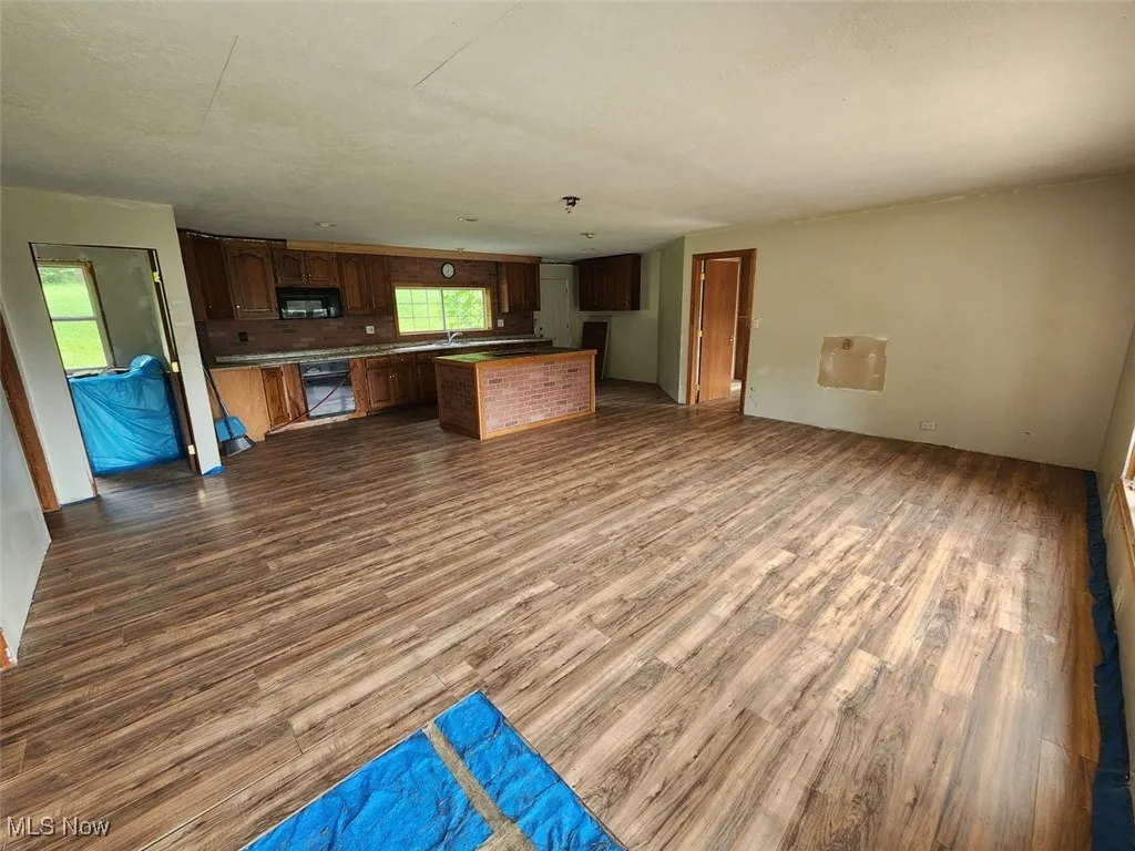 Kitchen featuring open floor plan, dark wood-style flooring, black microwave, a kitchen island, and oven