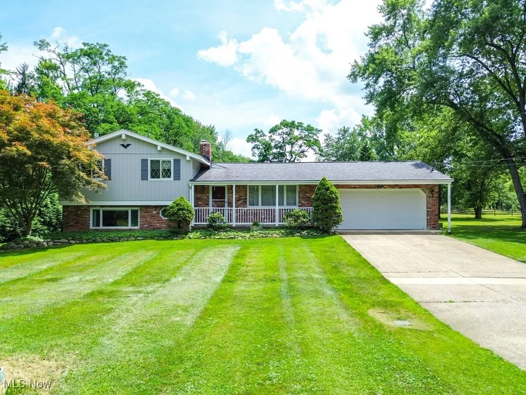 Tri-level home featuring brick siding, concrete driveway, a front yard, a chimney, and a garage