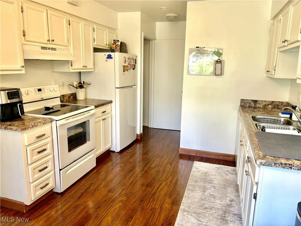 Kitchen featuring electric range, under cabinet range hood, refrigerator