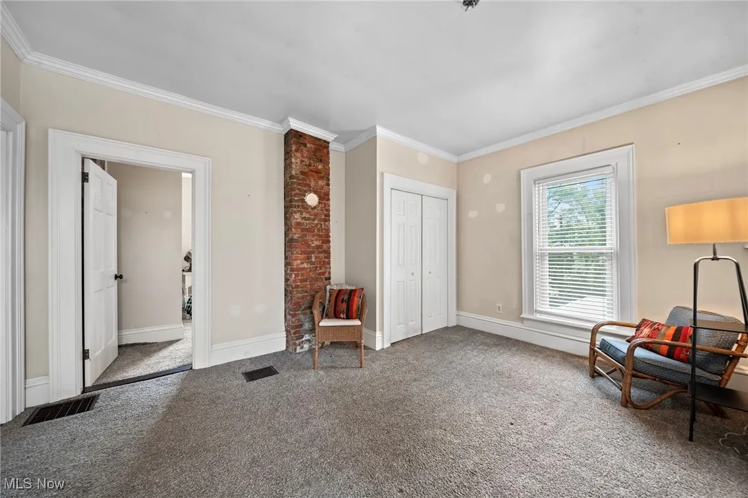 Sitting room with ornamental molding and carpet