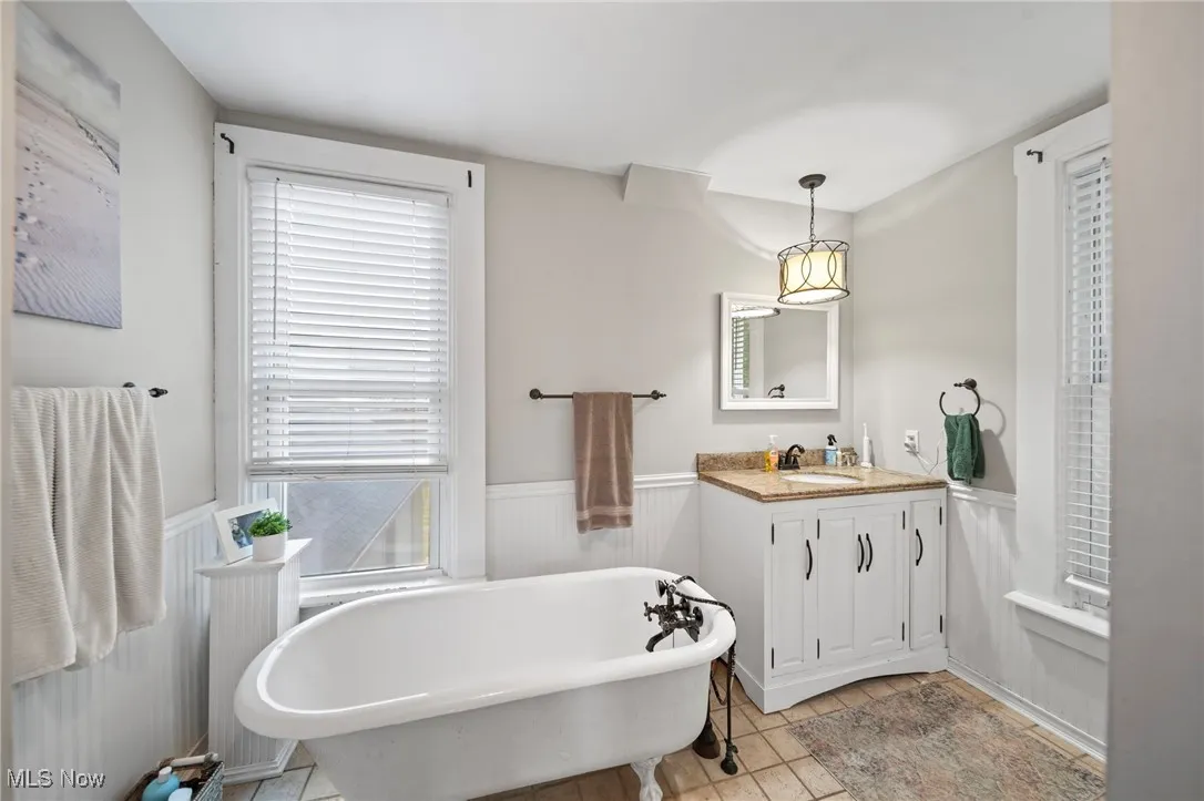 Bathroom with a wainscoted wall, vanity, plenty of natural light, and a freestanding bath