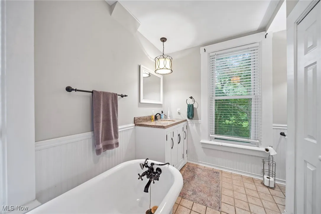 Bathroom featuring wainscoting, a soaking tub, and vanity