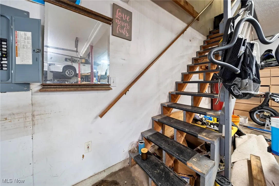Stairs featuring electric panel and concrete flooring