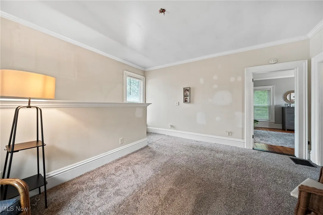 Carpeted empty room featuring healthy amount of natural light and crown molding