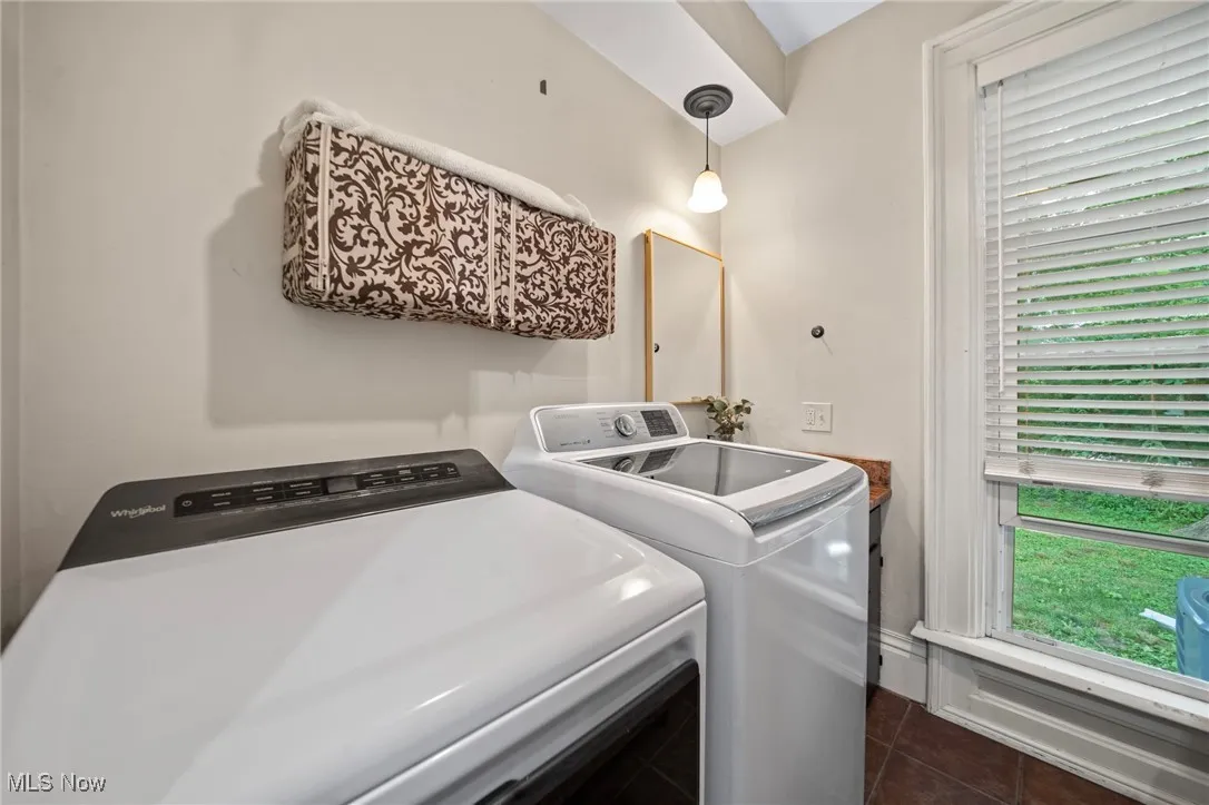 Laundry area with washer and dryer, dark tile patterned floors, and plenty of natural light
