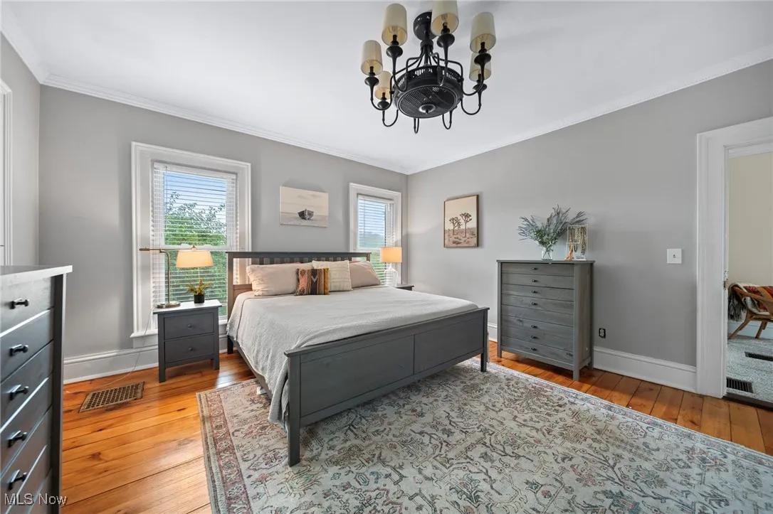 Bedroom featuring a chandelier, hardwood / wood-style flooring, and ornamental molding