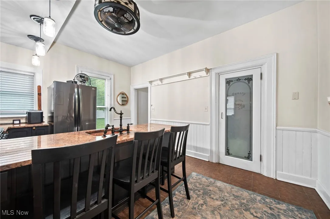 Dining area featuring a wainscoted wall and dark tile patterned flooring