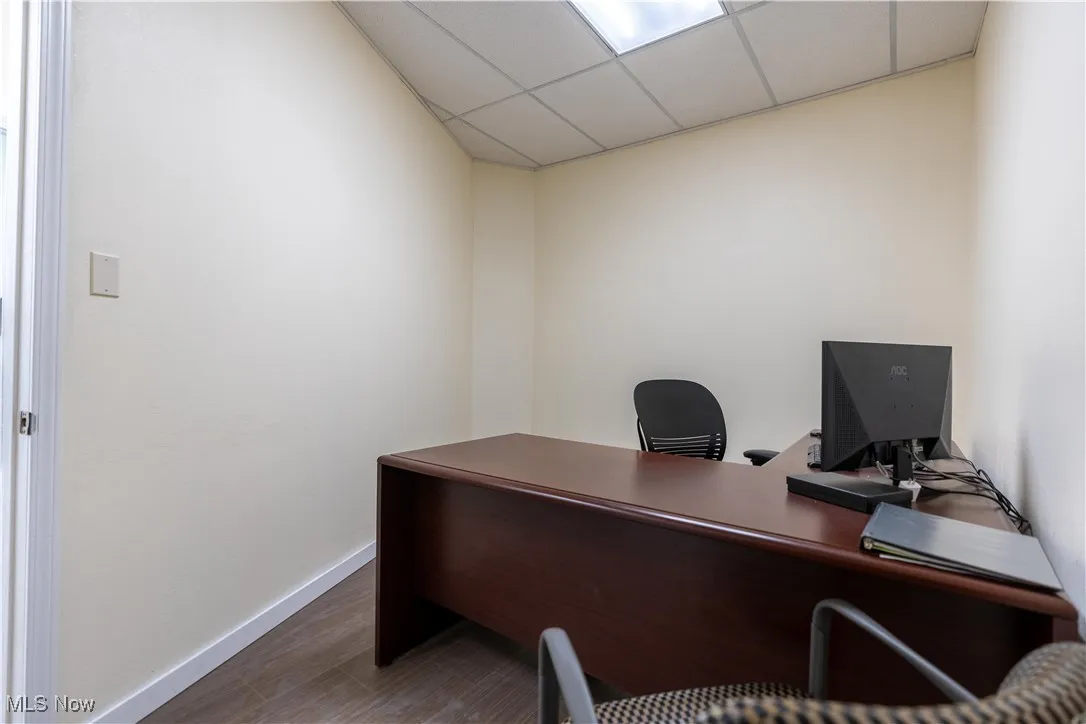 Office space with dark hardwood / wood-style flooring and a drop ceiling
