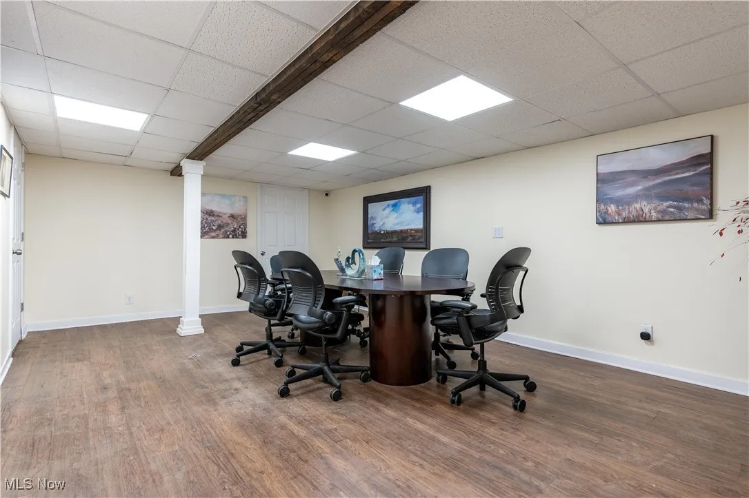 Office space with wood-type flooring, a drop ceiling, and ornate columns