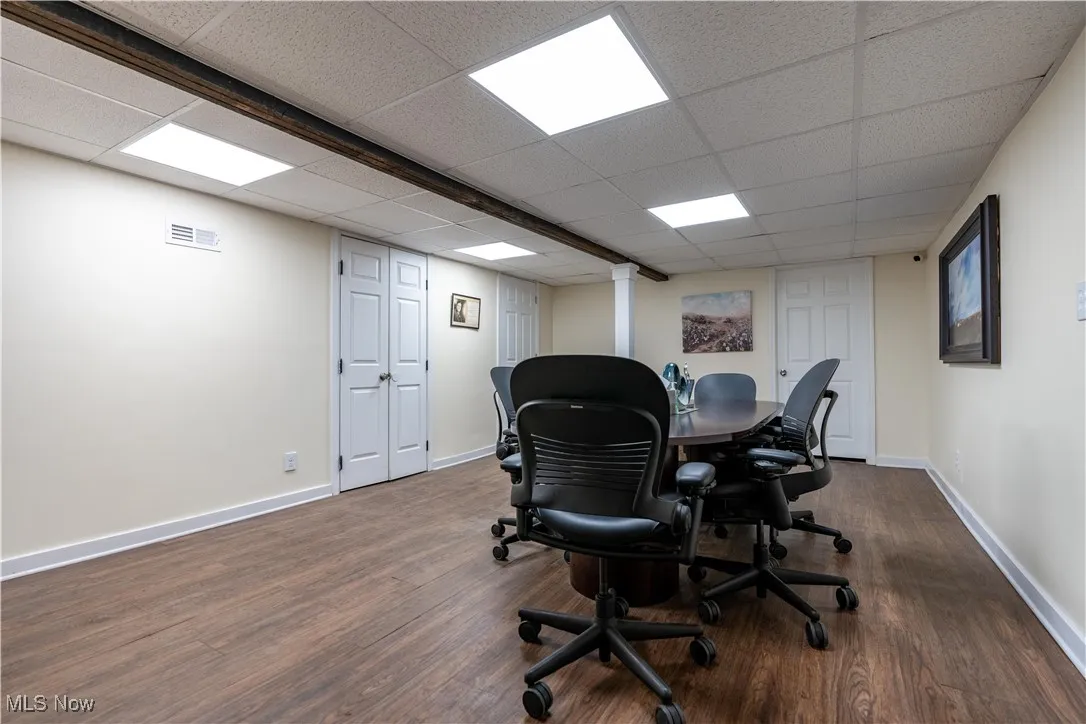Home office with a drop ceiling and dark hardwood / wood-style flooring