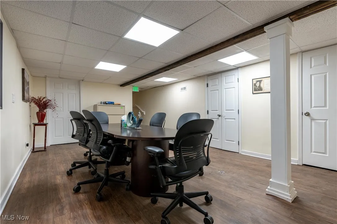 Home office with hardwood / wood-style flooring, a drop ceiling, and ornate columns