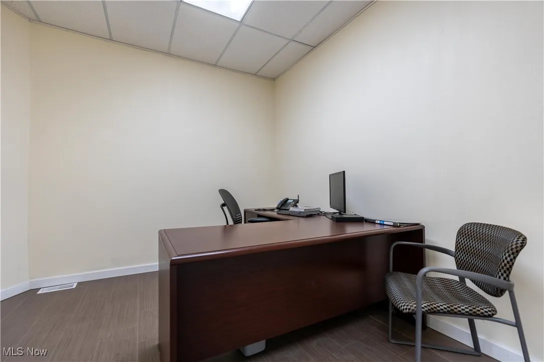 Office space featuring dark wood-type flooring and a drop ceiling