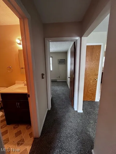 Hall featuring baseboards and a wall mounted air conditioner