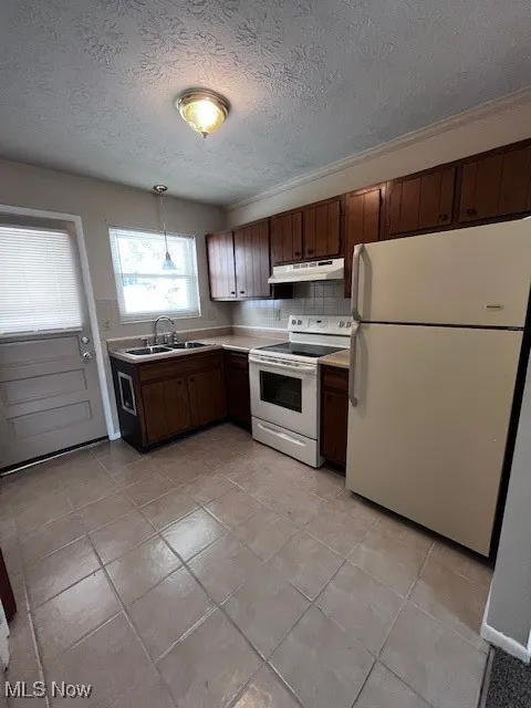 Kitchen featuring fridge, white electric stove, light countertops, a textured ceiling, and light tile patterned floors