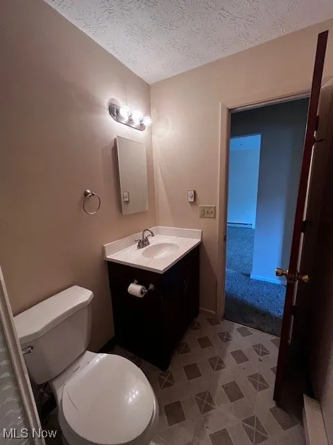 Half bathroom with a textured ceiling and vanity