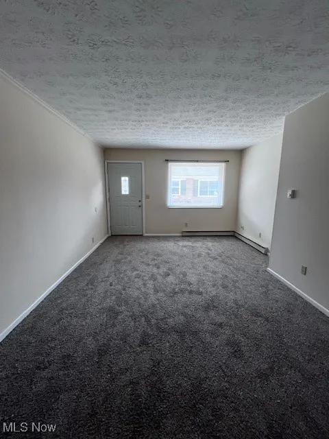 Unfurnished room featuring a textured ceiling and carpet floors