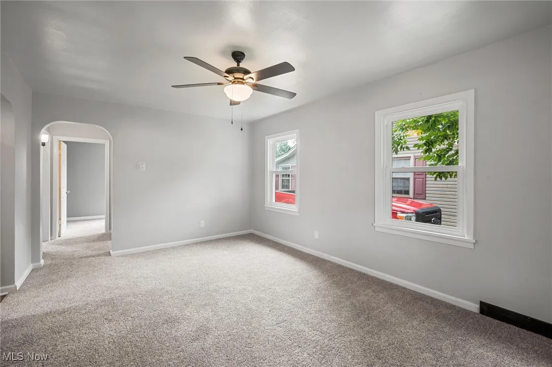 Living room featuring carpet floors, arched walkways, and a ceiling fan
