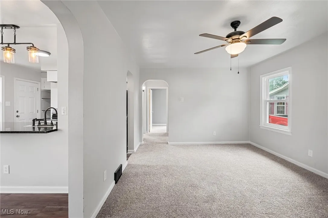 Living room with arched walkways, a ceiling fan, and carpet