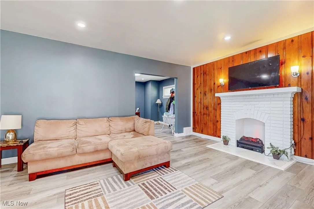 Living area featuring wooden walls, wood finished floors, recessed lighting, and a fireplace