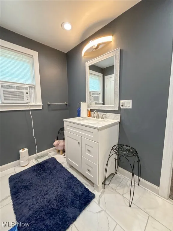 Bathroom with vanity, marble finish floors, and cooling unit