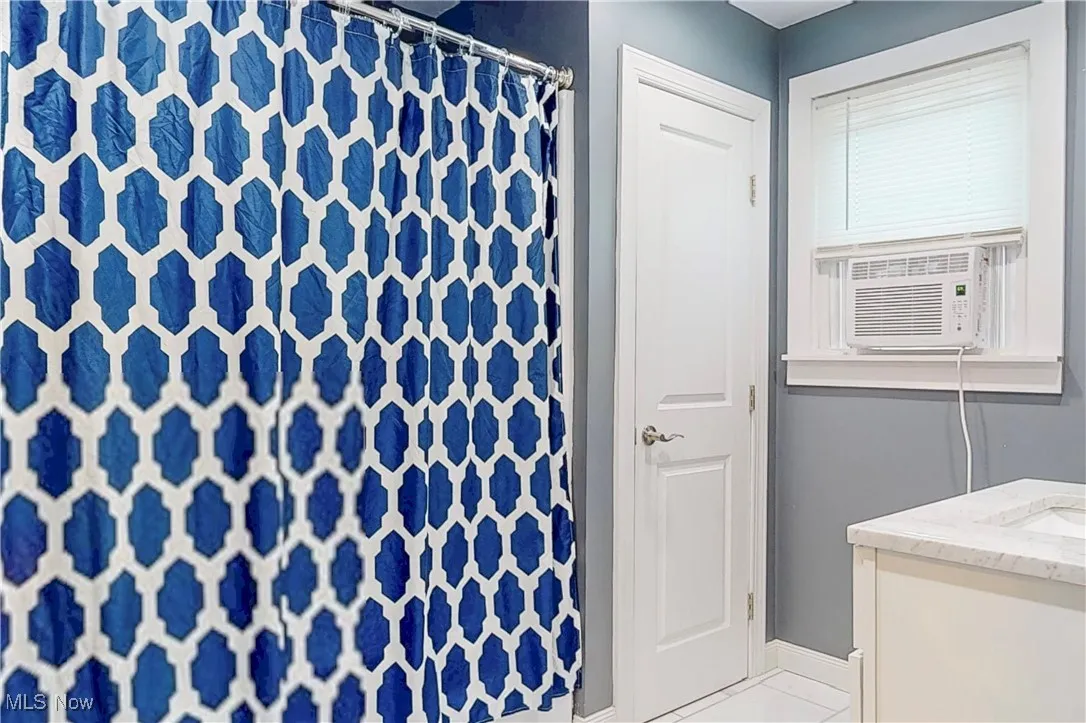 Full bathroom featuring vanity, a shower with shower curtain, tile patterned floors, and cooling unit