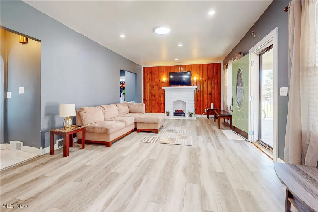 Living area featuring wooden walls, recessed lighting, light wood finished floors, and a fireplace