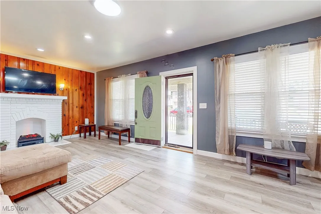 Living room featuring light wood-type flooring, wooden walls, and recessed lighting
