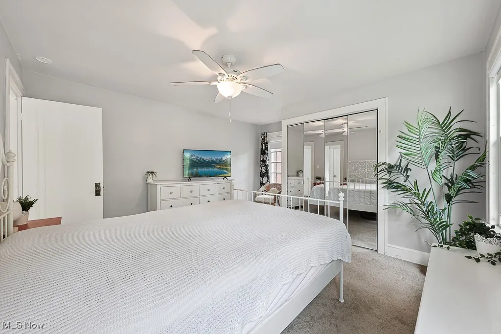 Carpeted bedroom with a closet, ceiling fan, and french doors