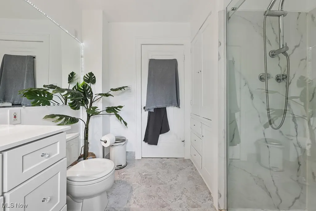 Full bathroom with a marble finish shower and vanity