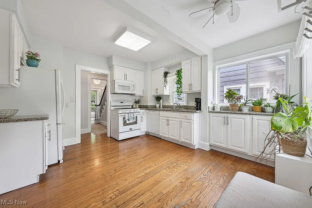 Kitchen featuring white appliances, a ceiling fan, white cabinets, light wood finished floors, and backsplash