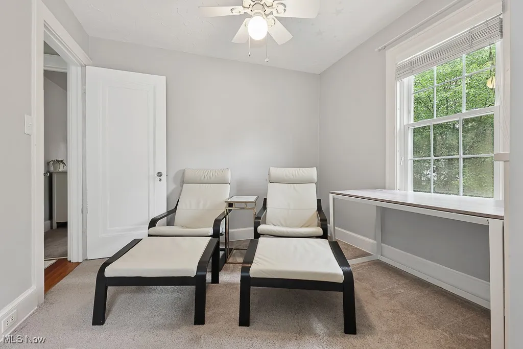 Sitting room with a ceiling fan and carpet